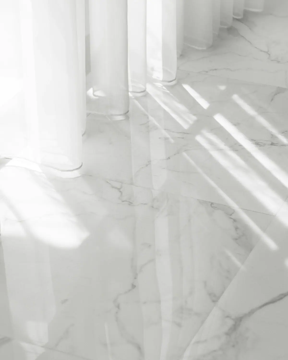 Sheer white curtains and morning light across a polished stone floor